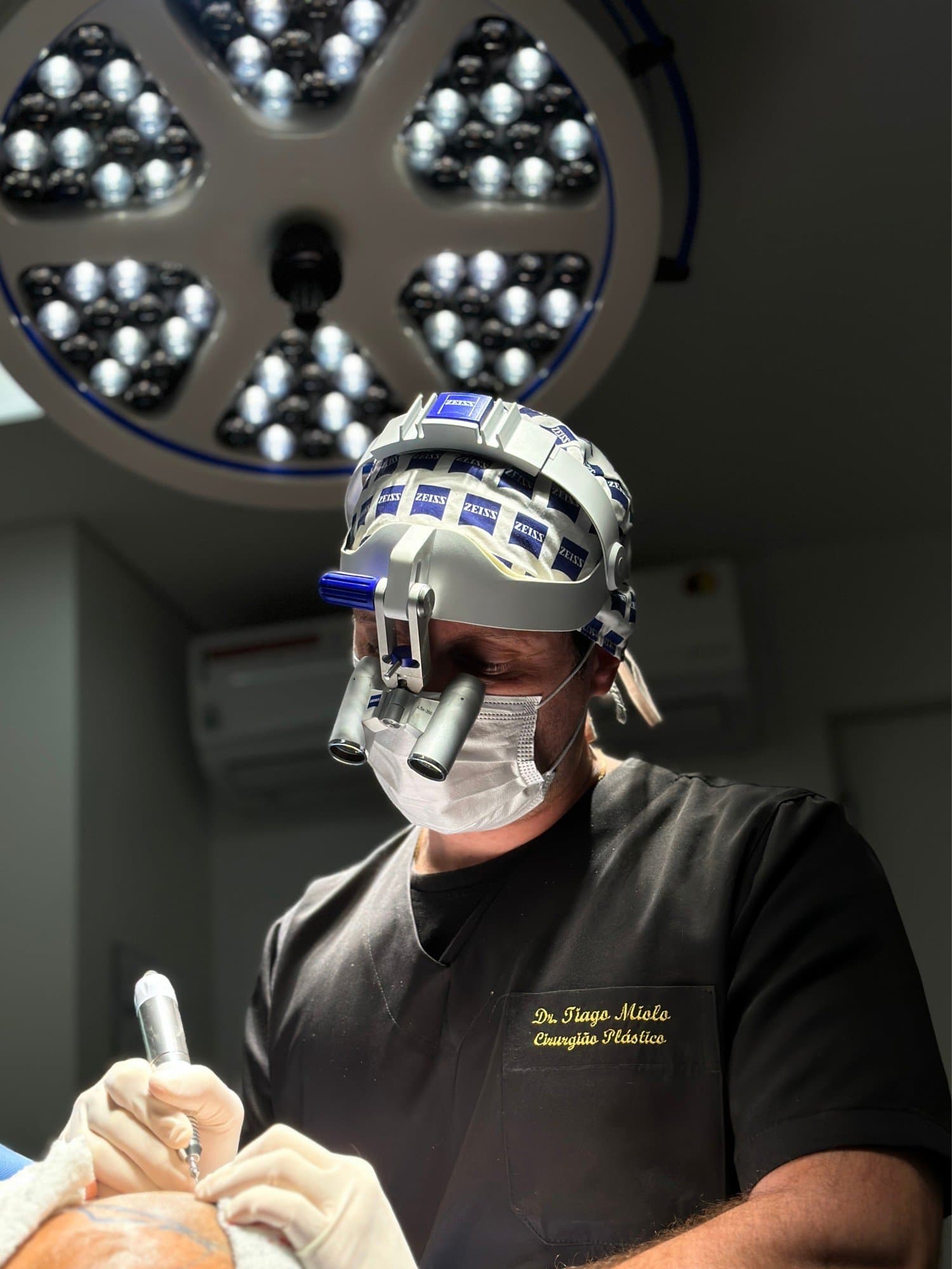 Dr. Tiago Miolo, cirurgião plástico, durante um transplante capilar com lupas cirúrgicas